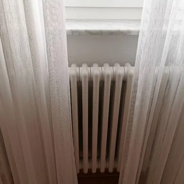 Lange gordijnen voor de radiator kunnen het convectieproces verhinderen