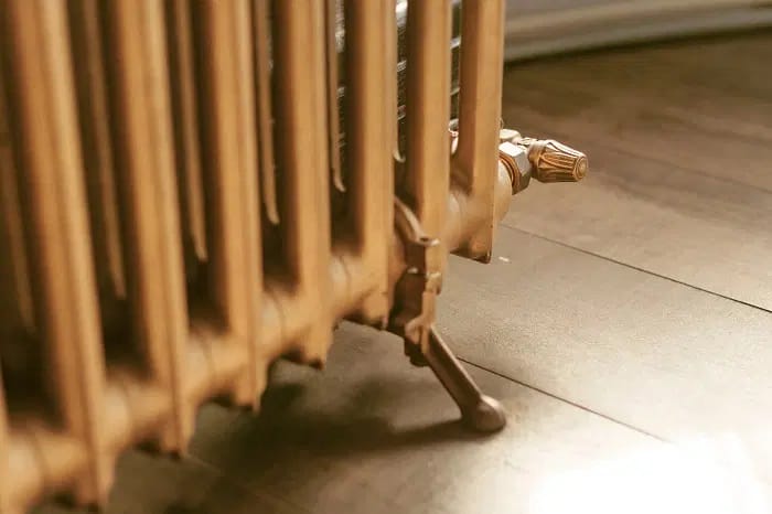 Een klassieke gietijzeren radiator en radiatorkraan met vintage afwerking in goud